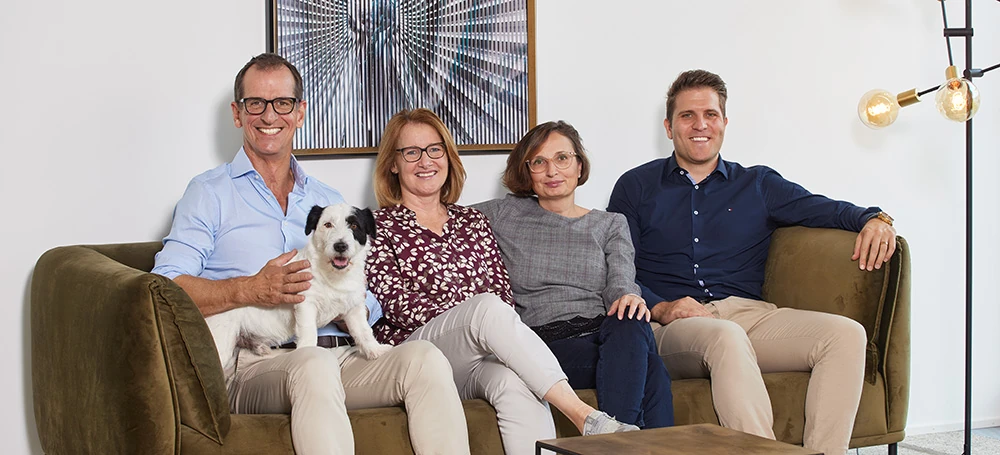 Das Team vom Bottleshop sitzt mit dem Hund Mio auf dem Sofa Das Team vom Bottleshop sitzt mit dem Hund Mio auf dem Sofa.
